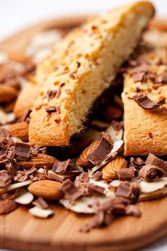 two pieces of cake sitting on top of a wooden plate covered in nuts and chocolate