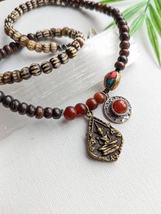 This unisex gemstone necklace features: ~ Bronze Phra Khun Phaen Amulet Pendant ~ Silver plated Carnelian Pendant  ~ Vintage Carnelian Beads ~ Black hematite beads  ~ Inlaid Tibetan brass turquoise and coral bead ~ Carved Brown and Smooth Brown Bone Beads ~ Raw brass lobster claw + Ring (with a vintage carnelian at clasp) * It is 20 inches long and perfect for layering with other JBO necklaces.  Thanks for shopping with JewelryByOri! Beaded Amulet Jewelry For Meditation, Meditation Beaded Amulet Jewelry, Vintage Gemstone Beads Jewelry For Meditation, Spiritual Pendant Crystal Necklace With Polished Beads, Festival Amulet Necklace With Gemstone Beads, Amulet Style Crystal Necklace With Gemstone Beads, Hand-strung Amulet Pendant Jewelry, Amulet Style Gemstone Beads Necklace For Festival, Bohemian Carnelian Necklaces For Meditation