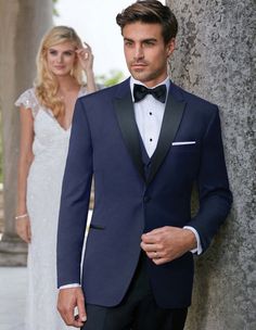 a man in a tuxedo standing next to a woman wearing a wedding dress