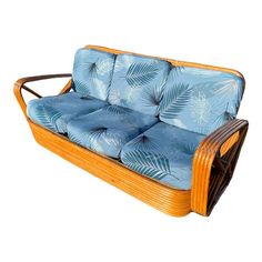 a wooden couch with blue cushions and palm leaves on the back, against a white background