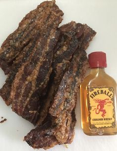 there is a bottle of barbecue oil next to some steak strips on the counter top