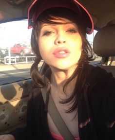 a woman sitting in the back seat of a car wearing a red hat and black jacket