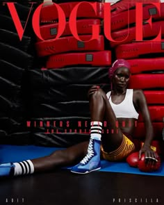 a woman sitting on top of a blue mat next to stacks of red and black tires