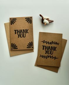 two thank you cards on top of each other next to a small toy bird and paper