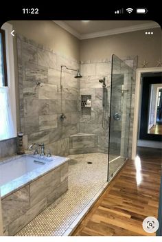 a large bathroom with a walk in shower next to a bathtub and wooden floors