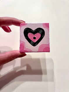 a hand holding a piece of paper with a heart painted on it