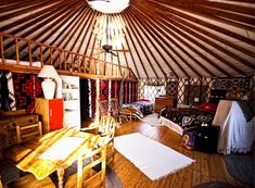 the inside of a yurt with wooden floors and walls, including a table in the center