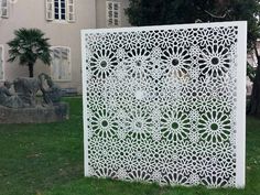 a large white sculpture sitting on top of a lush green field next to a building