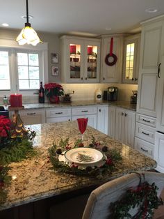 a kitchen decorated for christmas with white cabinets and granite counter tops