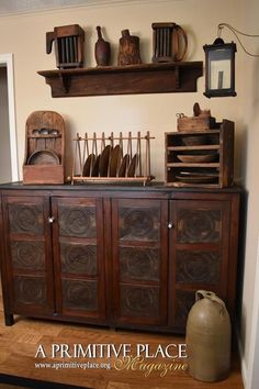 an old wooden cabinet with lots of dishes on top and shelves above it that are filled with pots, pans, and other kitchen utensils