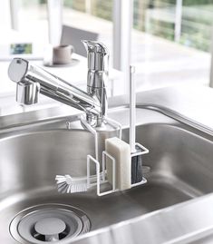 a toothbrush holder is attached to the side of a stainless steel sink with soap dispenser