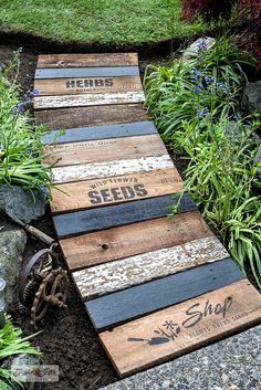 two wooden planks are laying on the ground in front of some plants and flowers