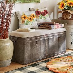 a wooden trunk sitting on top of a floor next to a vase filled with flowers