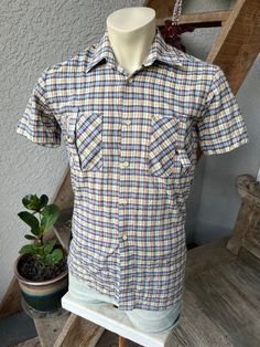 "This is a genuine vintage 1980s, short sleeve plaid shirt, in earthy colors with two barron-buckle chest pockets. Excellent vintage condition. Sweet style. Made in Romania by Braicons- seems like a 65% cotton, 35% polyester blend. Check the measurements: SIZE: Pit to Pit: 19\" Collar to hem: 30\" Sleeves: 8\" The tag says \"38.\" Check the measurements! The male mannequin would be 5'10\" 170 lbs. ITEM so" Plaid Camp Collar Shirt For Summer, Summer Plaid Camp Shirt With Camp Collar, Casual Plaid Short Sleeve Camp Shirt, Summer Plaid Short Sleeve Camp Shirt, Vintage Plaid Shirt With Pockets, Vintage Plaid Button-up Shirt, Vintage Plaid Collared Shirt, Vintage Plaid Cotton Shirt, Vintage Fitted Plaid Shirt