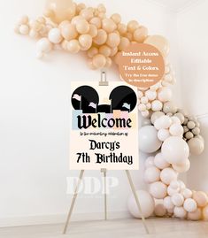 a welcome sign is surrounded by balloons in the shape of two heads and an arch