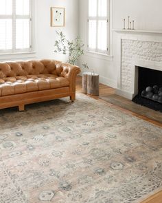 a living room with a couch, fireplace and rug on the floor in front of it