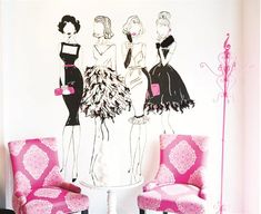 two chairs and a table in front of a wall with three women's dresses on it