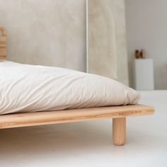 a wooden bed frame with white sheets and pillows