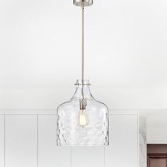 a clear glass light fixture hanging from a ceiling in a kitchen with white walls and cabinets