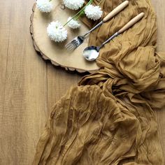 flowers and utensils laid out on a wood slice with spoons and forks