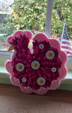 a pink crocheted vase sitting on top of a window sill next to an american flag