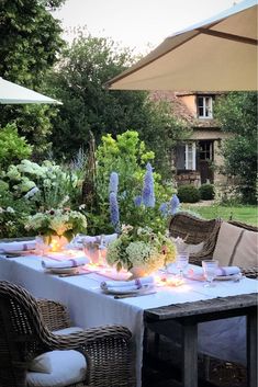 an outdoor dining table set with flowers and candles