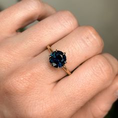 a woman's hand with a ring on it and a blue stone in the middle