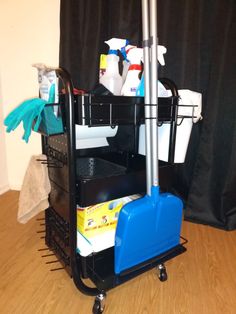 a black cart filled with cleaning supplies on top of a hard wood floor