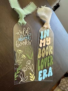 two bookmarks that are sitting on top of a wooden table, one has torn paper and the other has flowers