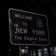 a street sign that says welcome to new york the empire state on it at night