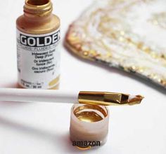 a close up of a gold paint and a white brush with some gold on it