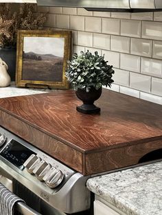 a potted plant sitting on top of a wooden table in a kitchen next to an oven