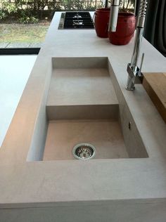 a modern sink in the middle of a kitchen counter with an open window behind it