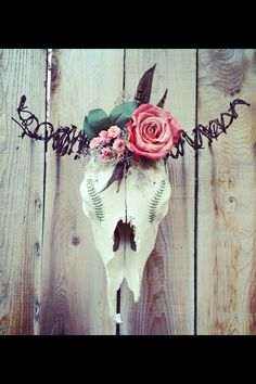 an animal skull with flowers on it's head and barbed wire around its neck