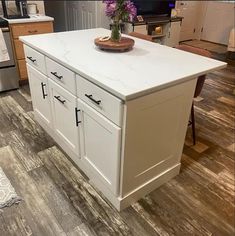 a kitchen island with white cabinets and drawers