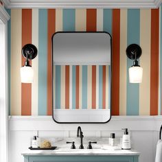 a bathroom with striped wallpaper and two sinks under a large mirror above the sink