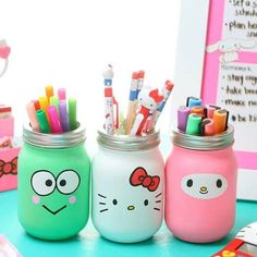 three mason jars with hello kitty markers and pencils in them on a blue table