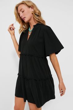 The Black Crepe Crawford Dress is exactly what we have been searching for — that perfect warm weather piece that you can throw on for morning cappuccinos and wear until cocktail hour. Featuring oversized flutter sleeves, ruffle detailing on the neckline and skirt, and a swing silhouette in a timeless color, this mini is the most flattering and flirty frock. Effortlessly whisking you from work to play, pair with sneakers and sunnies for a casual look then switch to wedges and statement earrings f Black Ruffle Sleeve Dress For Summer, Black Flutter Sleeve Dress For Vacation, Black Flutter Sleeve Beach Dress, Chic Short Sleeve Ruffle Dress For Beach, Tuckernuck Dress, Kenzo Dress, Stella Dress, Golf Dresses, Blythe Dress