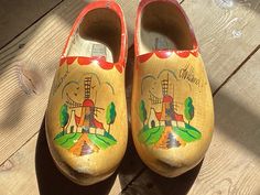 This pair of wooden shoes are large Menscshoes. They have "Holland" painted on both shoes. They also have a windmill scene painted on the top of the shoe. They are size 44/45. There is wear to the finish. They are 13" long by 5" wide by 5 1/2" tall. Clogs And Mules, Mule Clogs, Etsy Vintage, Holland, Clogs, The Top, Kitchen Decor