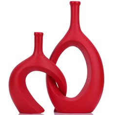 two red vases sitting next to each other on a white surface, one is shaped like a heart