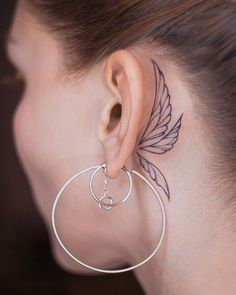 a close up of a person with a tattoo on their left side of the ear