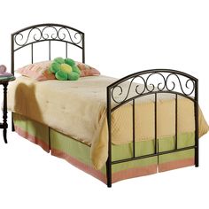 a metal bed frame with a green flower on the headboard and foot board, against a white background