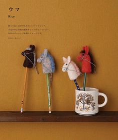 three small stuffed animals sitting on top of a shelf next to a cup with pencils in it