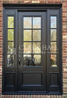 a black double door with two sidelights and glass panels on the front of a brick building