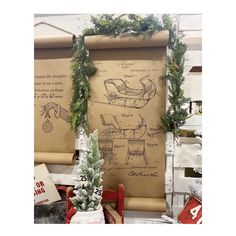 christmas decorations are on display in front of an old sheet of paper with drawings and evergreens