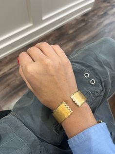 a person wearing a gold bracelet with an eye on it's wrist and one hand resting on the other