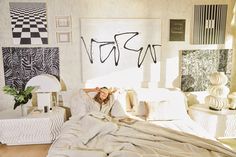 a woman laying on top of a bed in a room with white walls and furniture