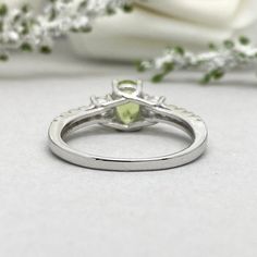 a close up view of a ring with a green stone in the center on a white background