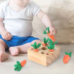 a baby sitting on the floor playing with carrots