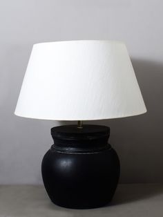 a black table lamp with a white shade on the top and bottom part of it